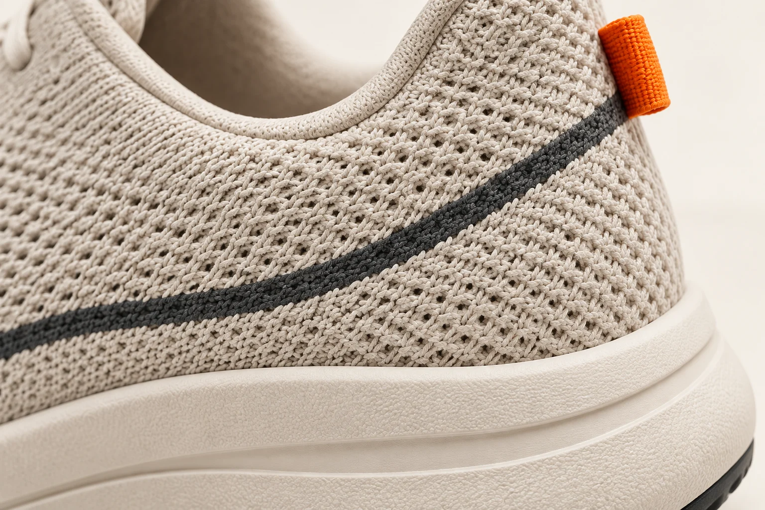 Close-up of the chalk knit, charcoal seam and orange fabric heel tab