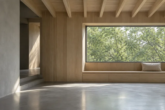 A pale timber room with a long window, built-in bench and soft light on a grey floor.