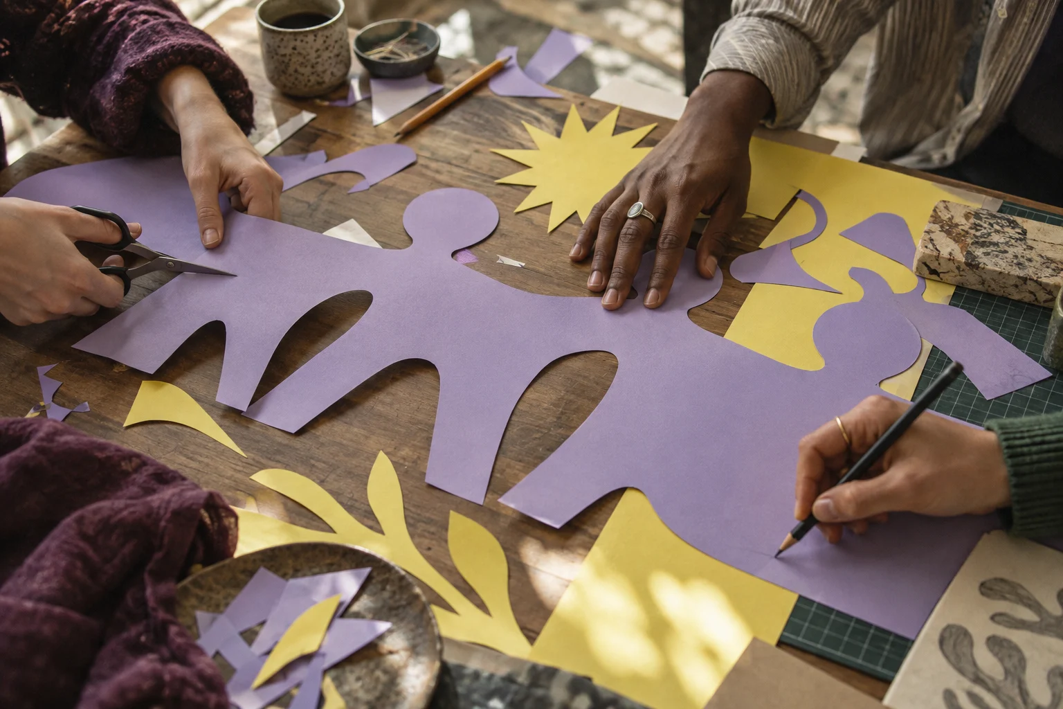 Friends cutting lavender and yellow paper around a shared worktable